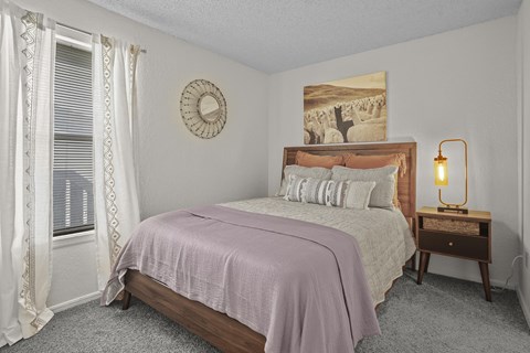 A bedroom with a bed, nightstand, and window.