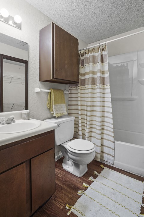 A white toilet sits in a bathroom with a brown cabinet and striped shower curtain.