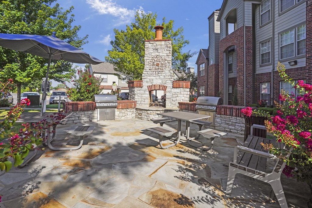 A patio with a stone fireplace and seating area.