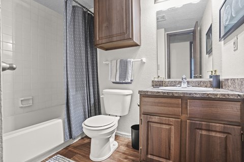 A white toilet is in a bathroom with a wooden cabinet.