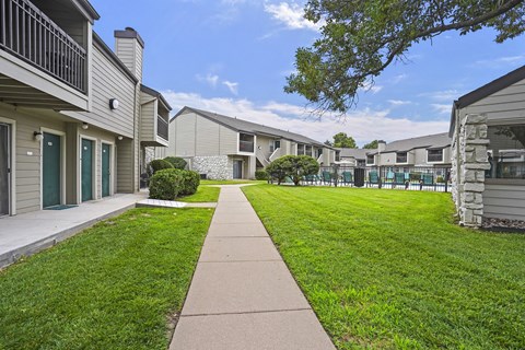A walkway leads through a grassy area between apartment buildings.