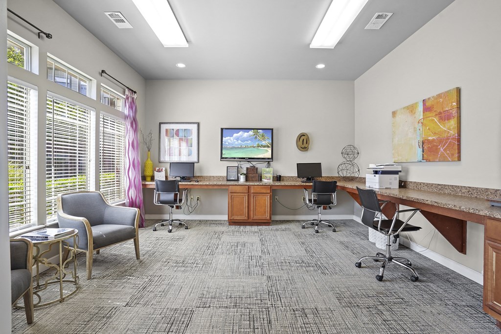 A room with a grey carpet and a desk with a computer on it.