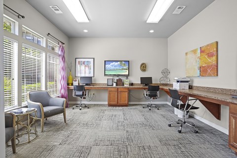 A room with a grey carpet and a desk with a computer on it.