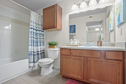 A bathroom with a white toilet and a wooden cabinet.