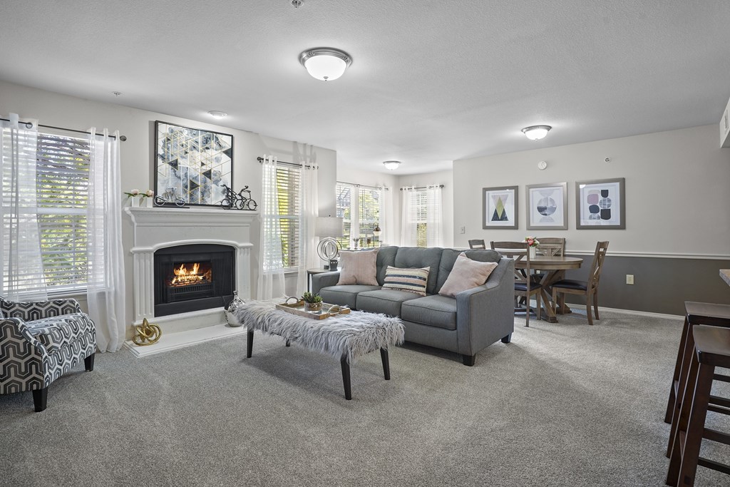 A living room with a fireplace and a grey couch.