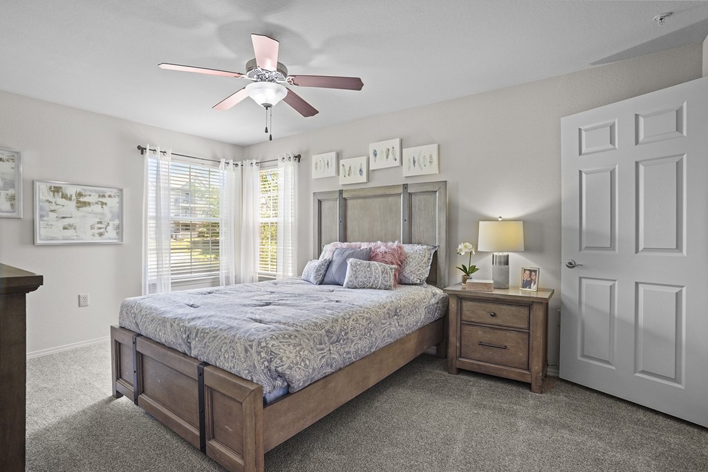 A bedroom with a bed, nightstand, and a ceiling fan.