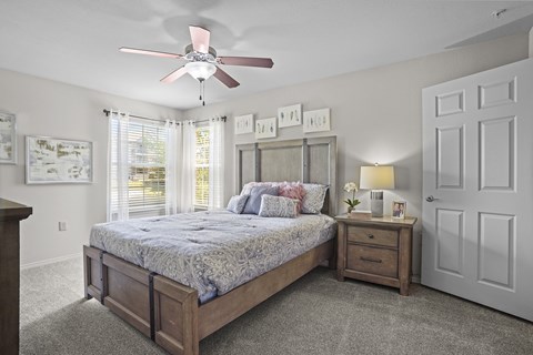 A bedroom with a bed, nightstand, and a ceiling fan.