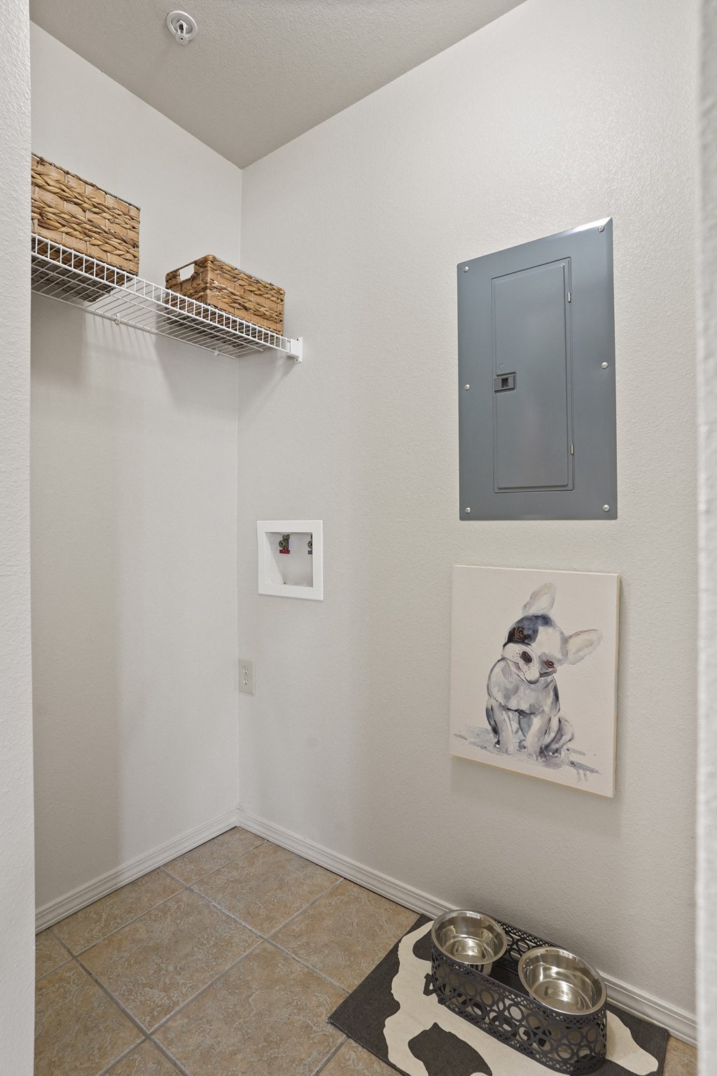 A hallway with a grey door, a painting of a dog, and two bowls on a mat.