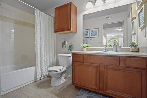 A white toilet sits under a white shower curtain in a bathroom.