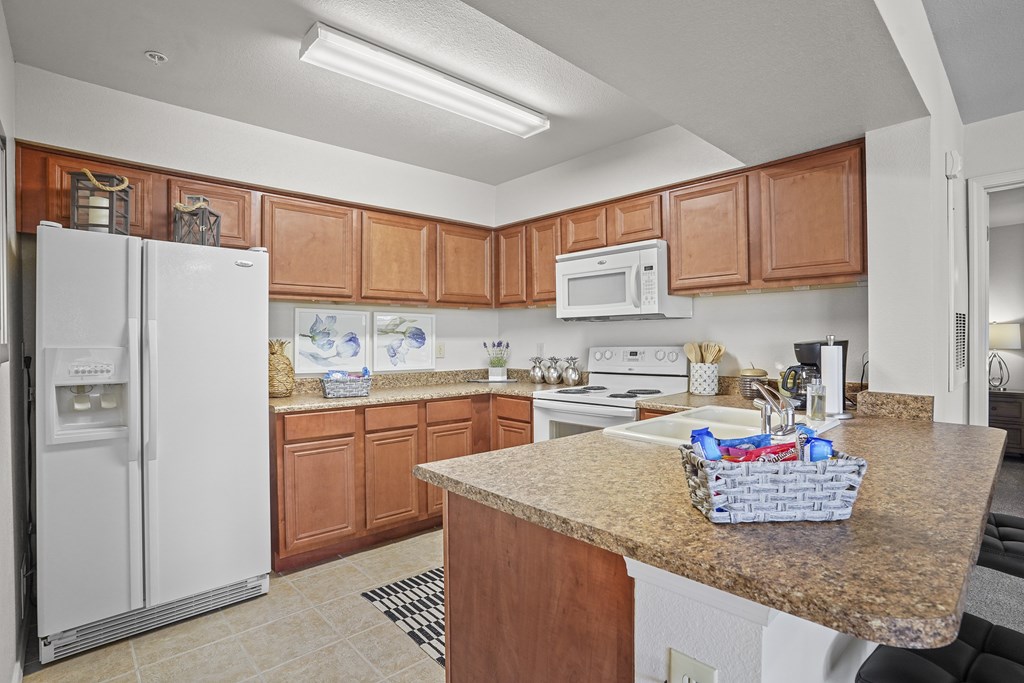 A kitchen with a white refrigerator and wooden cabinets.