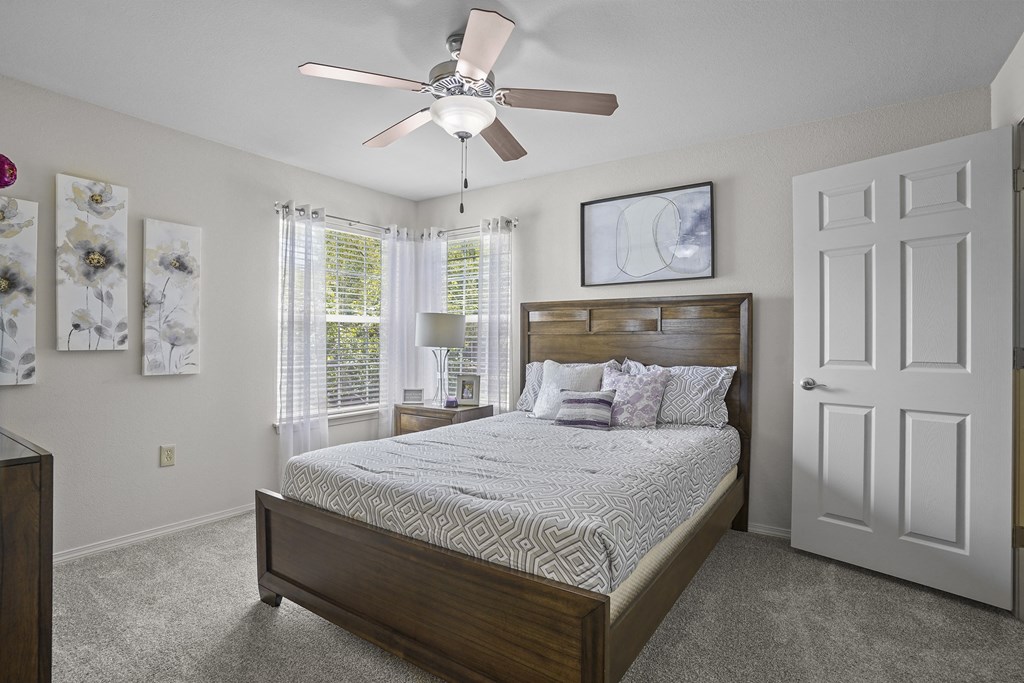 A bedroom with a large bed and a ceiling fan.