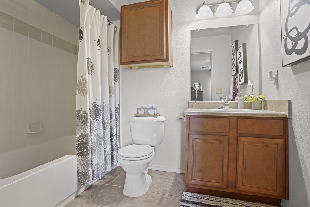 A white toilet sits in a bathroom next to a white bathtub.