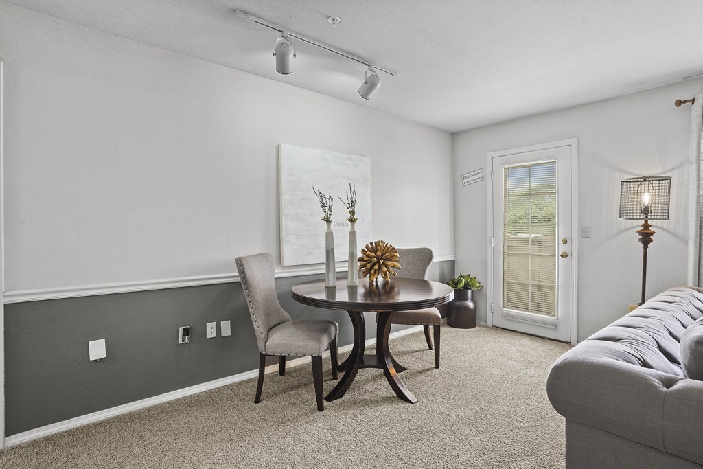 A grey sofa sits in a room with a round table and chairs.