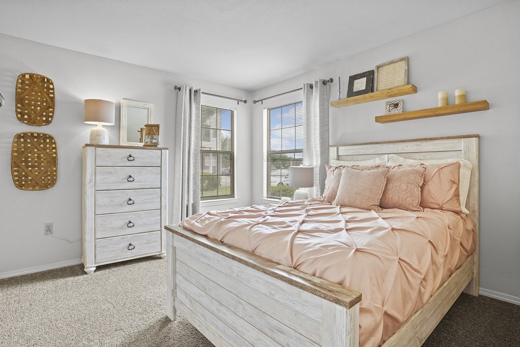 A bedroom with a bed, dresser, and window.
