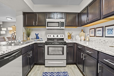A modern kitchen with dark wood cabinets and stainless steel appliances.
