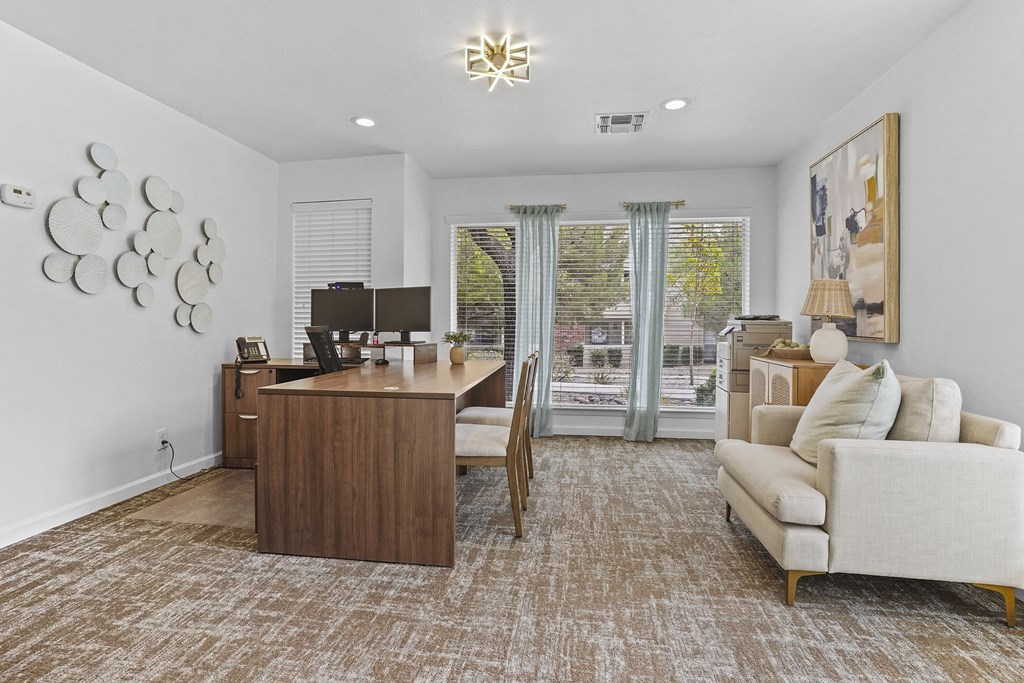 A room with a brown carpet and a wooden desk with a computer on it.