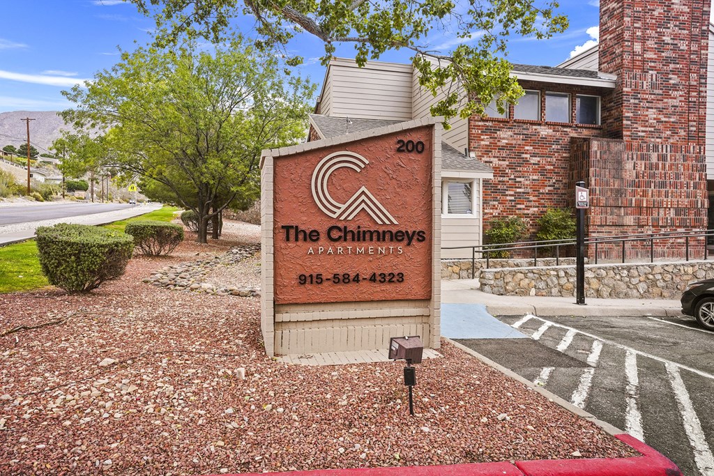 The Chimneys Apartments sign in front of a brick building.