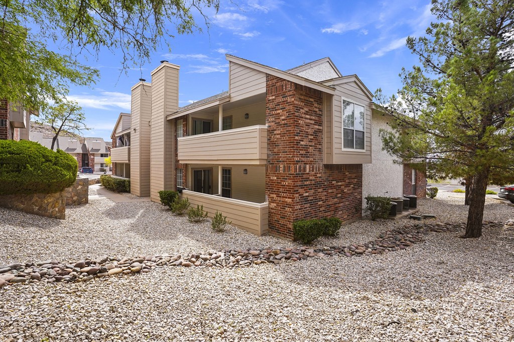 A modern house with a stone wall and a gravel driveway.