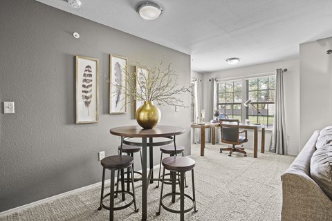 A living room with a grey wall and a round table with a gold vase on it.