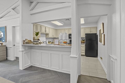 A kitchen with a black fridge and white cabinets.