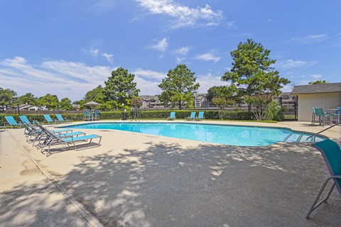 A large outdoor swimming pool surrounded by blue lounge chairs.
