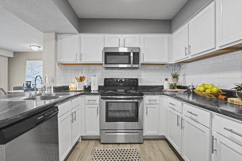 A modern kitchen with white cabinets and stainless steel appliances.