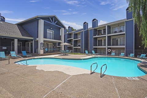 A swimming pool in front of a building with a blue sky in the background.