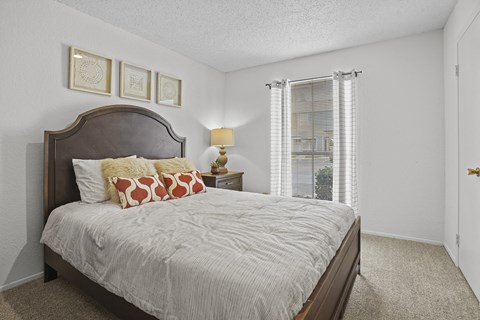 A bedroom with a large bed and a window with blinds.