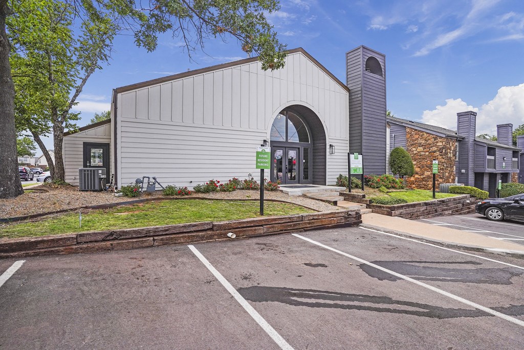A parking lot in front of a building with a green sign.