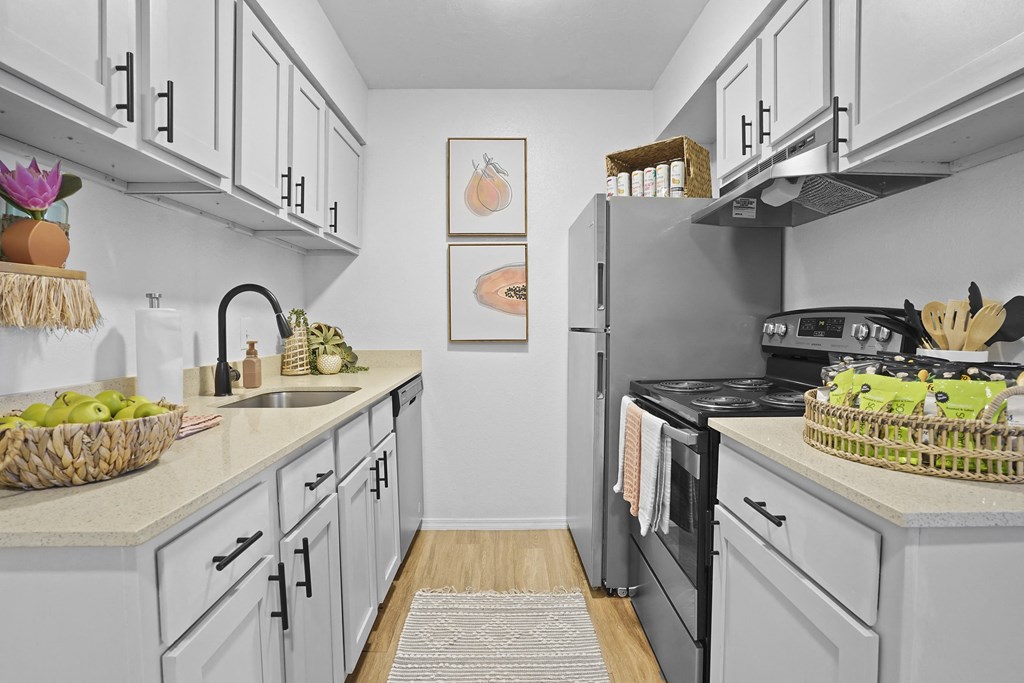 A kitchen with a white counter top and grey cabinets.