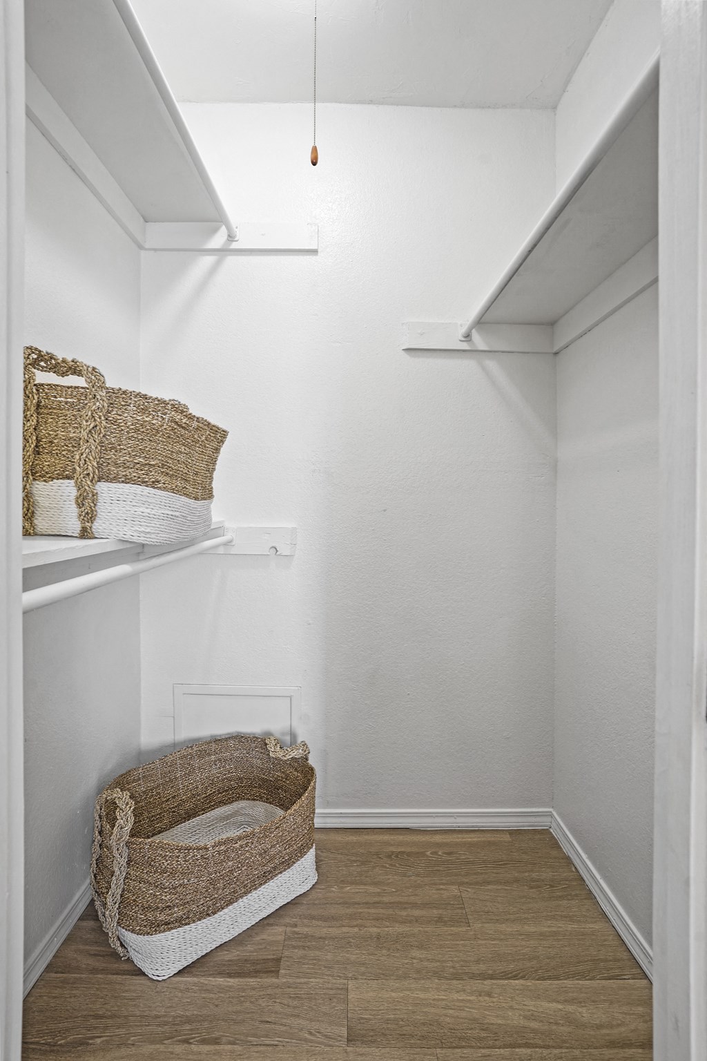 A small white closet with a basket on the floor.