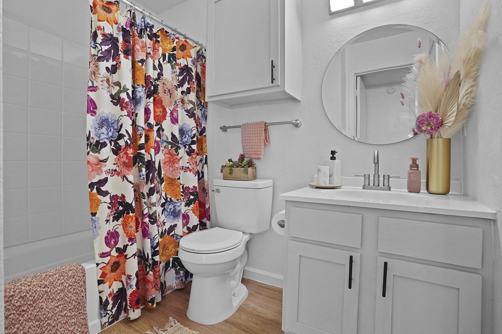 A white toilet with a floral shower curtain in a bathroom.