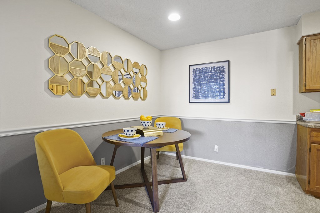 A yellow chair sits in front of a table with a cup and saucer on it.