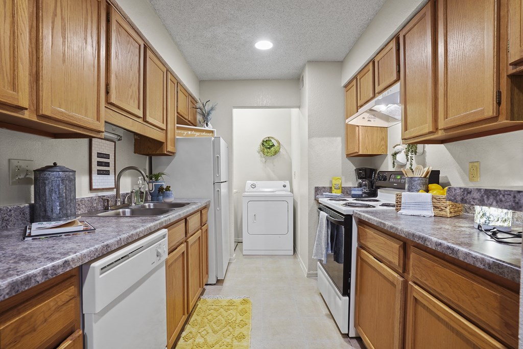 A kitchen with wooden cabinets and a white dishwasher.