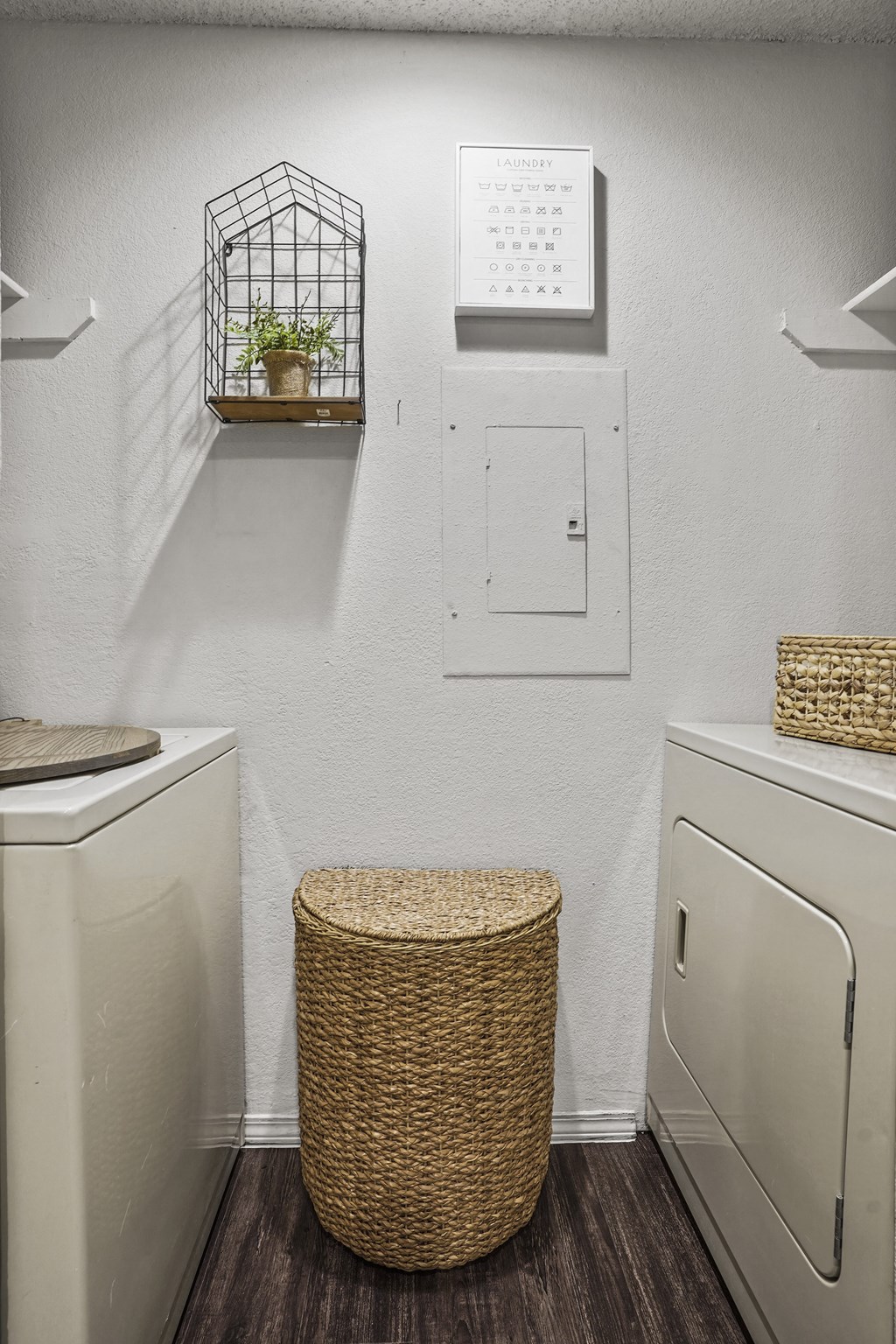 A laundry room with a basket stool and a washer and dryer.