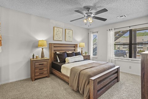 A bedroom with a bed, nightstands, and a ceiling fan.