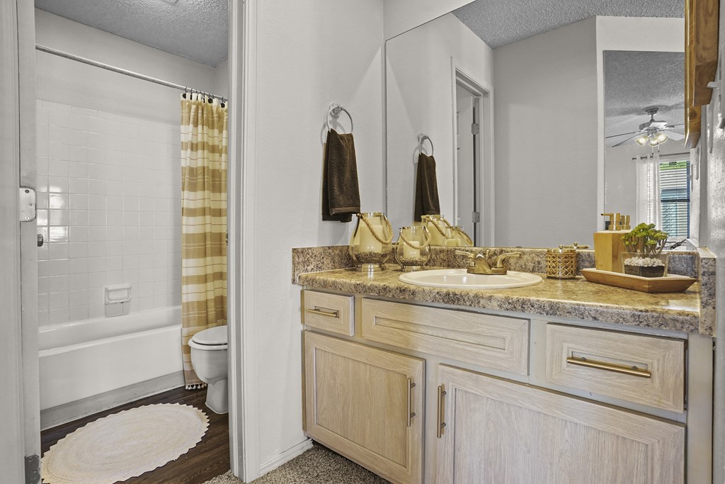 A bathroom with a toilet, sink, and mirror.