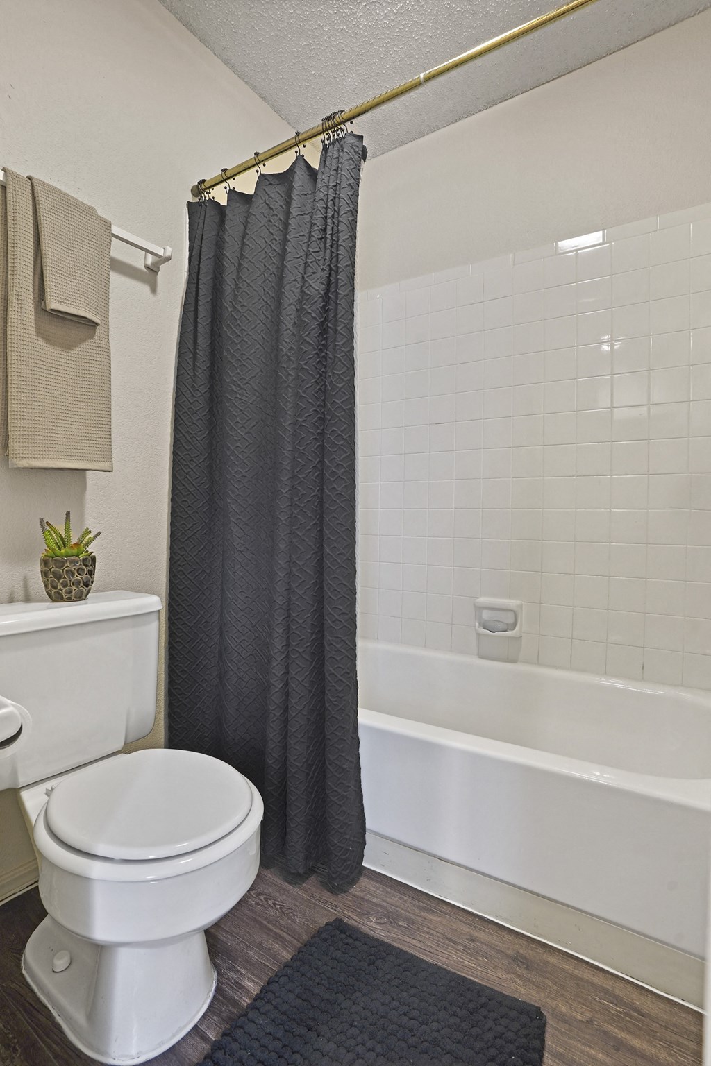 A bathroom with a white toilet and a black shower curtain.