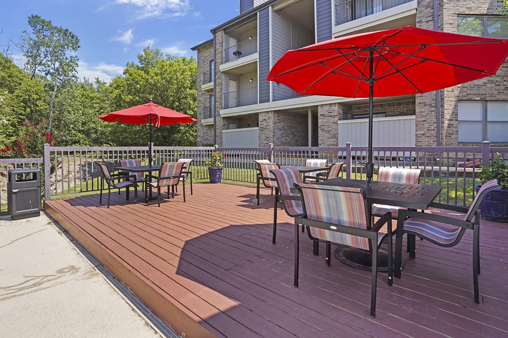 A red umbrella is on a wooden deck.
