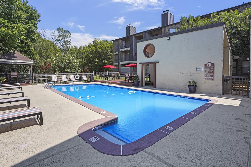 A small pool with a purple border and a white building in the background.