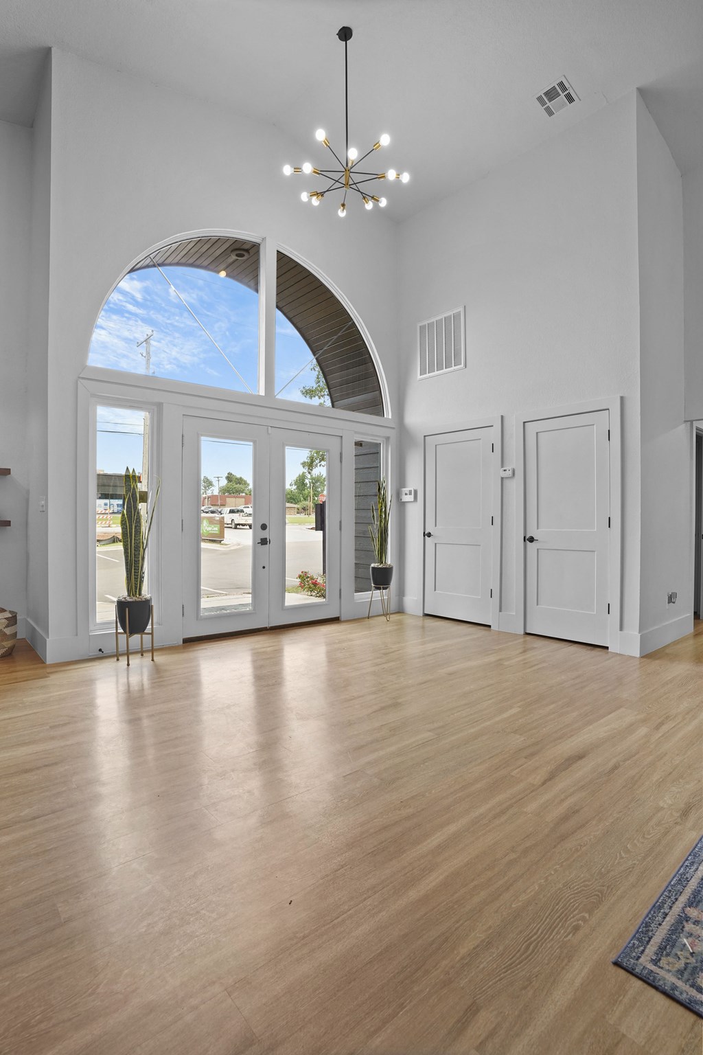 A room with a large arched window and wooden floors.