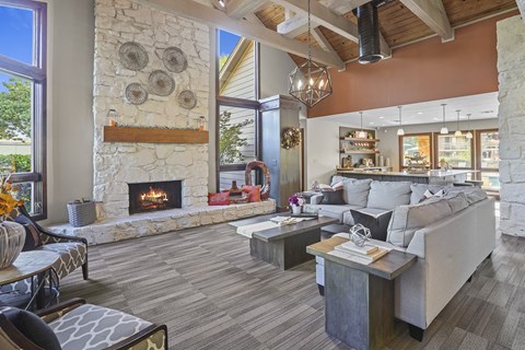 A living room with a stone fireplace and a grey couch.