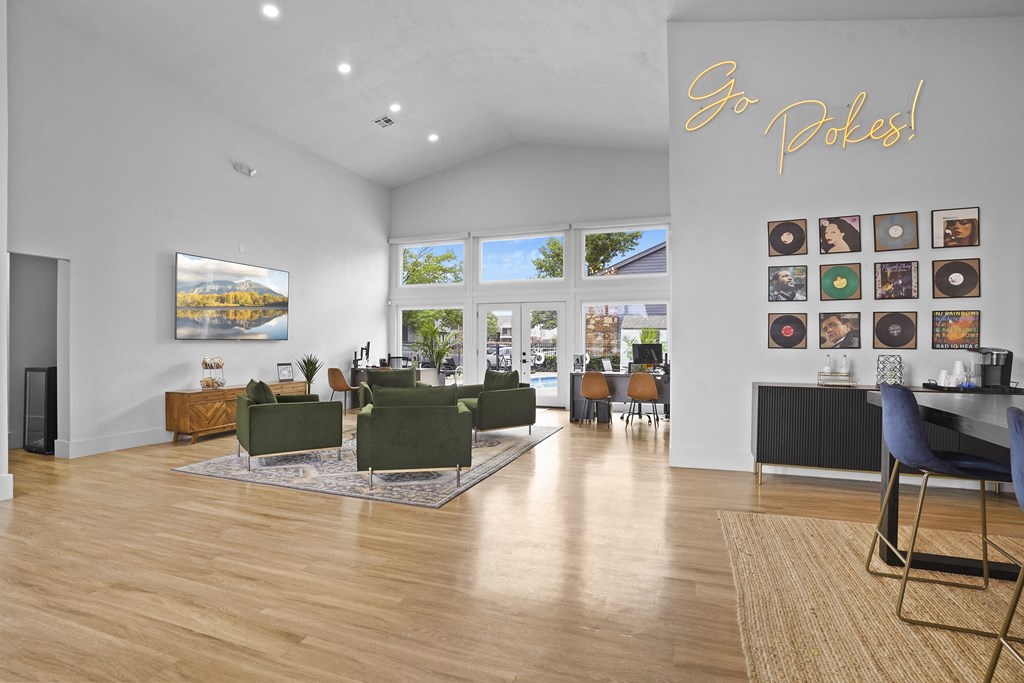 A living room with a large couch and a wall with pictures and a sign that says "Go Pokes!".