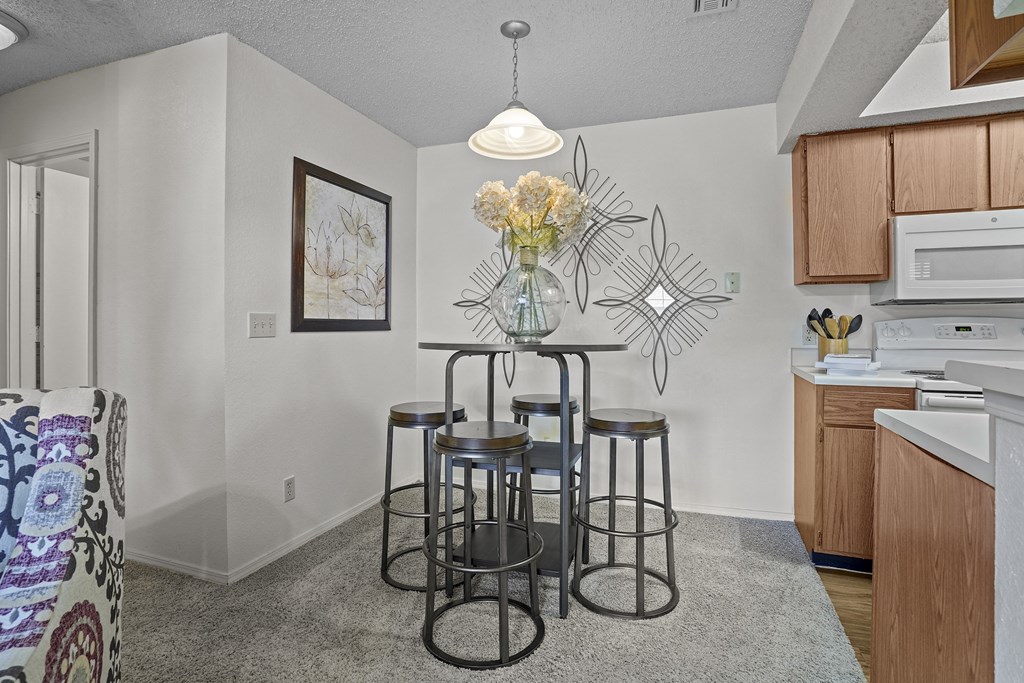 A kitchen area with a bar stool and a vase of flowers.