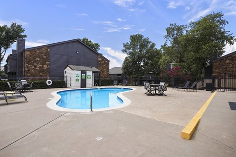A small pool in a concrete area with a yellow barrier.