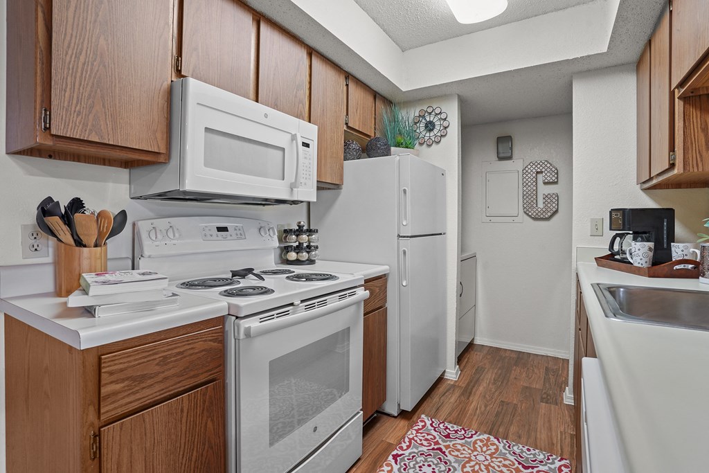 A kitchen with white appliances and wooden cabinets.