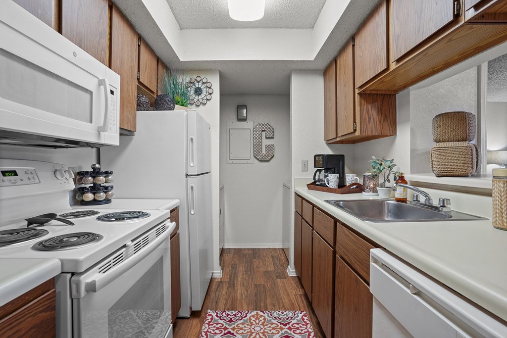 A kitchen with white appliances and wooden cabinets.