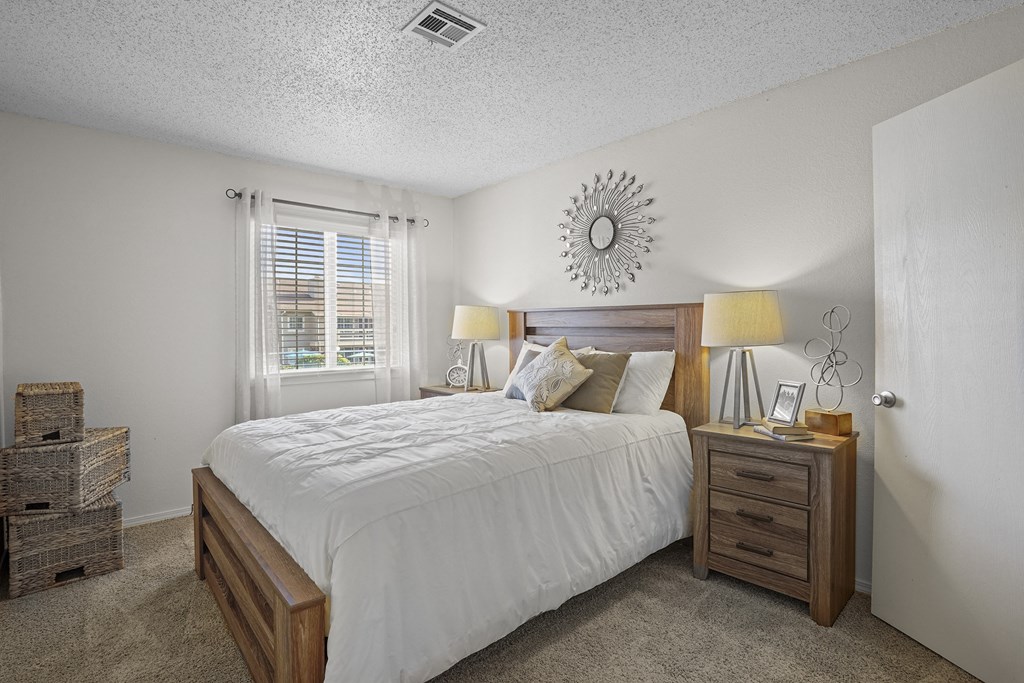 A bedroom with a bed, nightstand, and window.