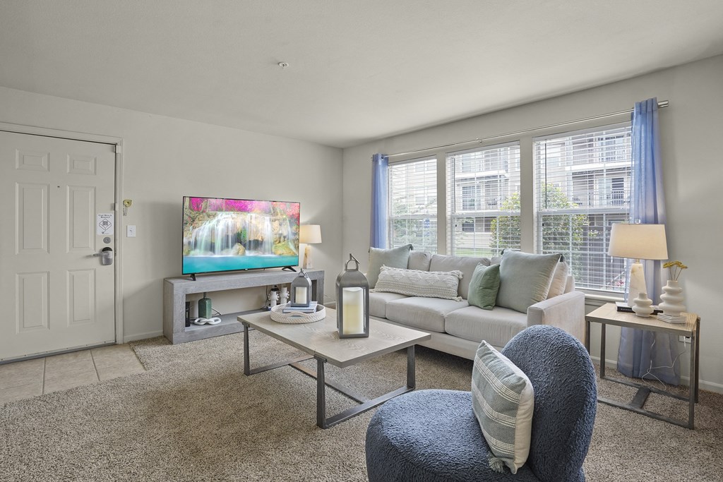 A living room with a grey couch, a blue chair, and a television.