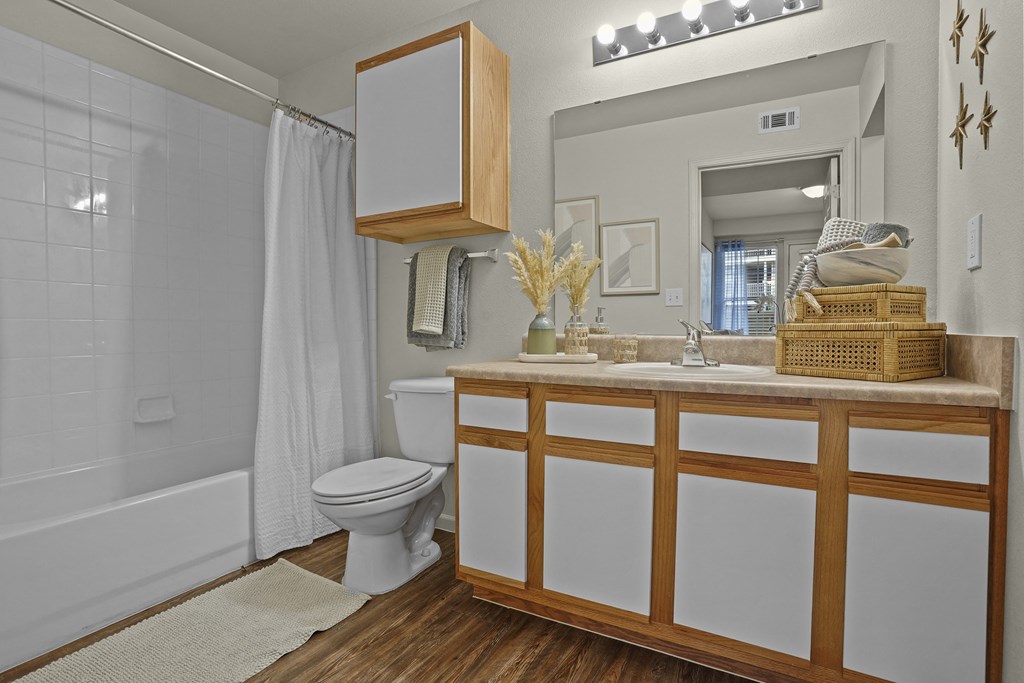 A white bathroom with a wooden vanity and a toilet.